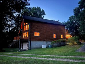 A two-story wooden house with a balcony, a stone staircase, and a well-maintained lawn. - Maxwell Reserve • Private Forest Retreat • Sleeps 14 (Tionesta)