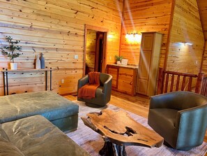 A cozy room with wooden walls, a sofa, a chair, a coffee table, and a cabinet. - Maxwell Reserve • Private Forest Retreat • Sleeps 14 (Tionesta)