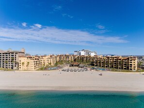 Ein Strandhotel mit mehreren Gebäuden, einem Sandstrand und strahlend blauem Himmel.