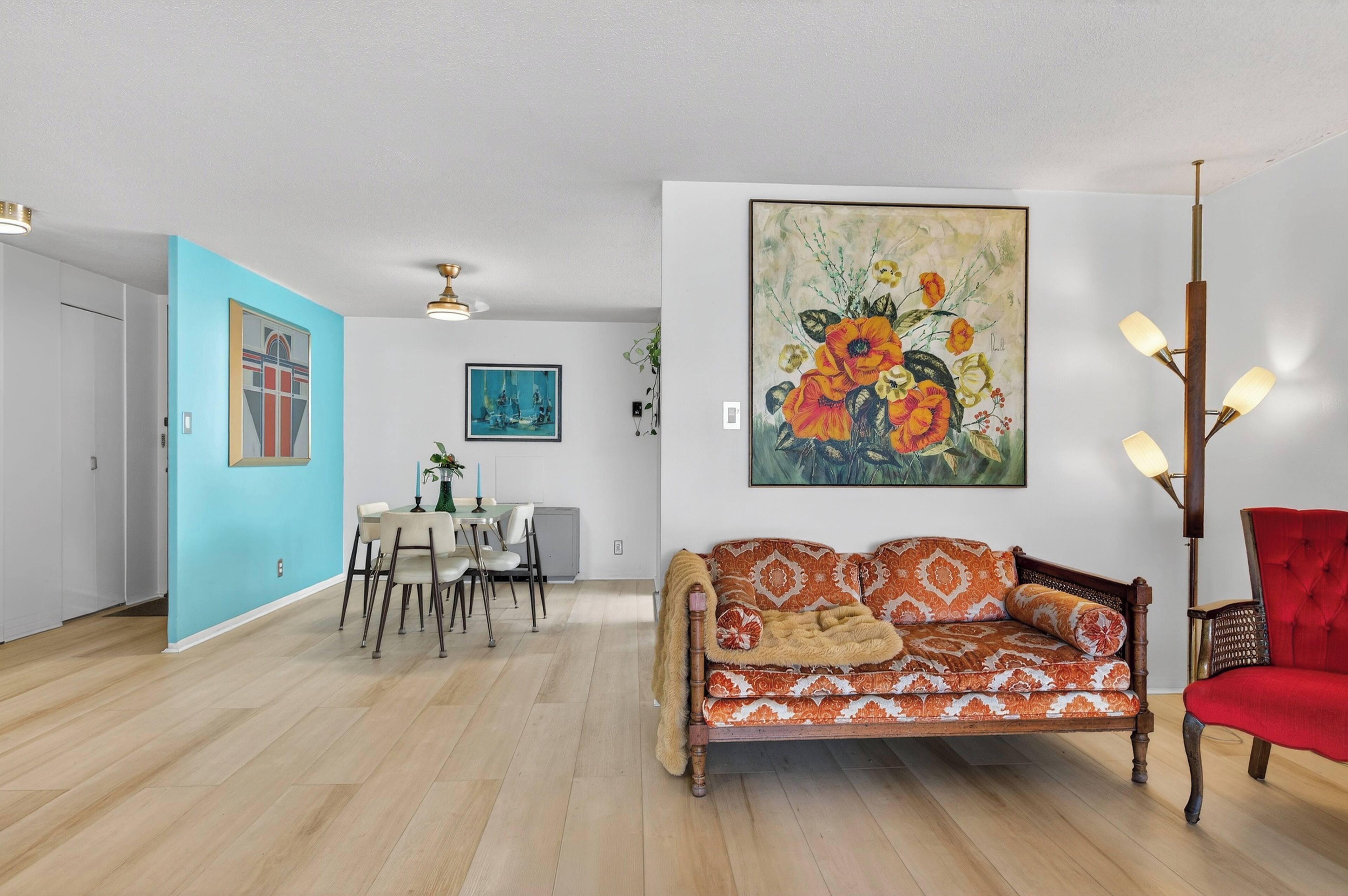 Un salon avec un canapé, une table à manger et des chaises, et un tableau accroché au mur.