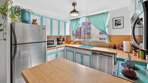 A compact kitchen with a stainless steel refrigerator, a microwave, a sink, and a stove. - Mile High Mid-Century Oasis, Light-Filled Central Denver Walkable Neighborhood!! (Denver)
