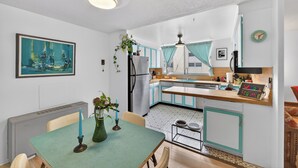 A compact kitchen with a dining area, a ceiling fan, a clock, and a framed painting. - Mile High Mid-Century Oasis, Light-Filled Central Denver Walkable Neighborhood!! (Denver)
