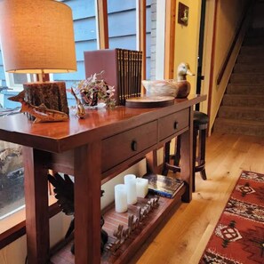 Una consola de madera con adornos, una lámpara y vistas a una escalera.