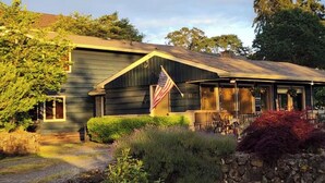 A two-story house with a porch, an American flag, and a stone wall in the front yard.