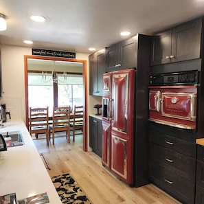 A modern kitchen with dark cabinetry, a red refrigerator, and a built-in oven.