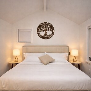 Ein Bett mit Kopfteil, zwei Nachttische mit Lampen, eine an der Wand befestigte Baumdekoration und ein Fenster.