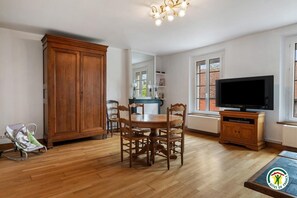 Une pièce comprenant une table à manger en bois, des chaises, un téléviseur, un meuble et une grande armoire en bois.
