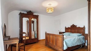 Une chambre à coucher avec un lit en bois, une chaise en bois, une armoire en bois et un bureau.