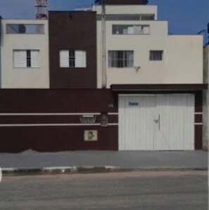 Een gebouw met een witte garageklep, een bruine muur en een raam met zonwering.
