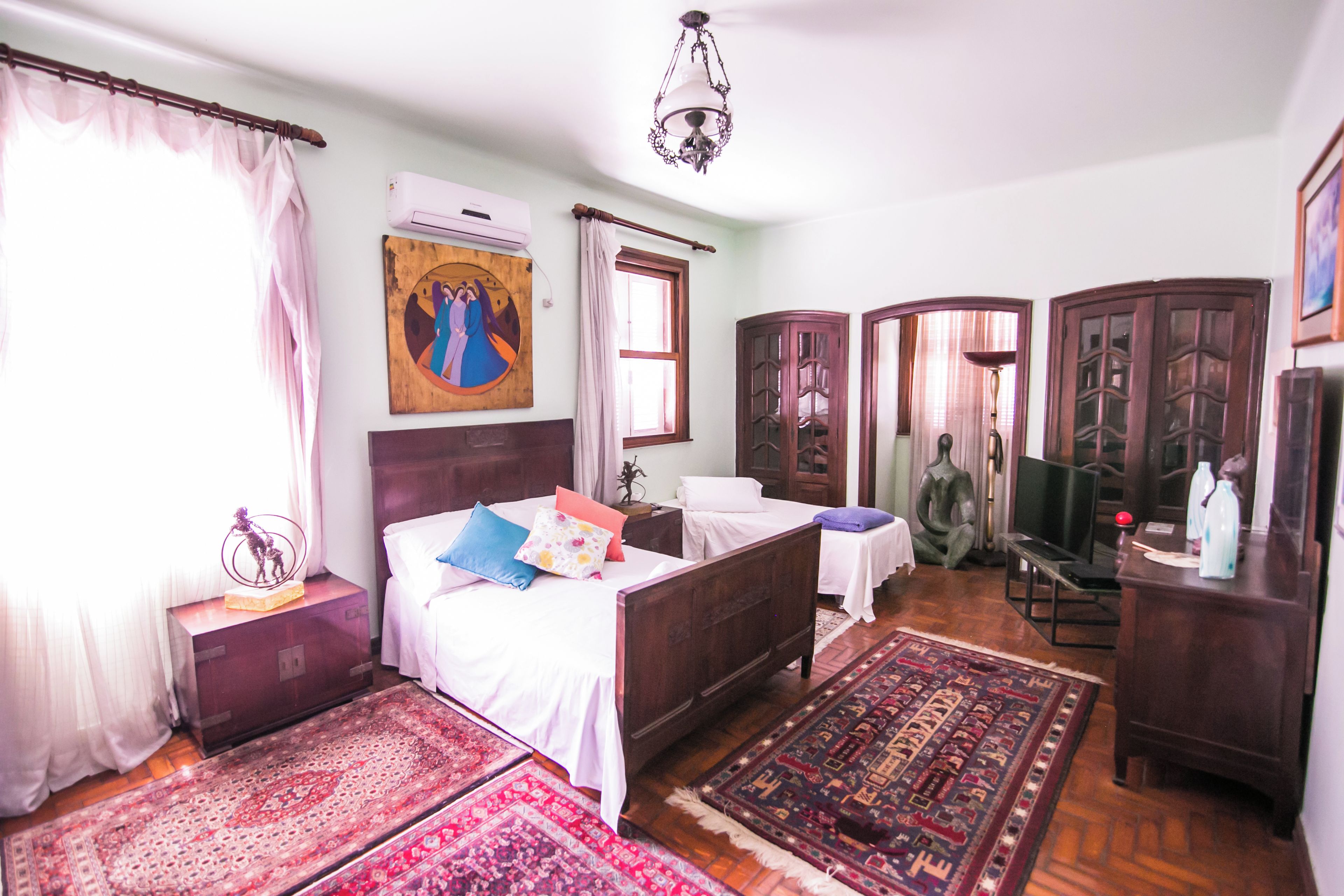 Ein traditionell eingerichtetes Zimmer mit Bett, Schreibtisch, Sessel, Fernseher und einer Zierleuchte.