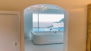 A bathroom with a large bathtub, a chandelier, and a view of the sea. - Serene 8-bedroom resort with AC in beautiful El Nido (El Nido)