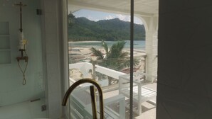 A bathroom with a shower, a glass door leading to a balcony with a view of a beach and mountains. - Serene 8-bedroom resort with AC in beautiful El Nido (El Nido)