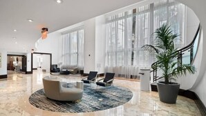 A spacious lobby with a marble floor, a round seating area, and large windows. - Sorrento 704 (Miami Beach)