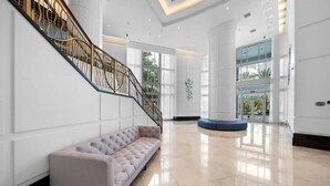 A spacious lobby with a modern staircase, a seating area, and a large glass entrance. - Sorrento 704 (Miami Beach)