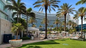 A hotel with a pool area, palm trees, and a covered seating area. - Sorrento 704 (Miami Beach)