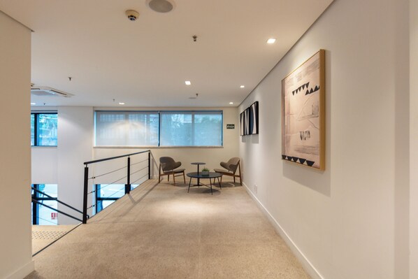 A modern interior with a staircase, a small table with chairs, and a large framed artwork on the wall. - RCT Hospedagens - Paulista Consolação (São Paulo)