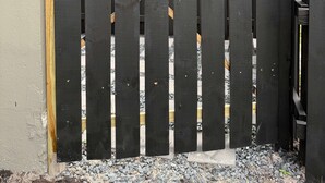 Una cancelada de madera con un cartel que dice 'Welcome', un pestillo metálico y una base de concreto.