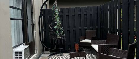 Un patio con mobiliario exterior, una planta en maceta y un suelo estampado.