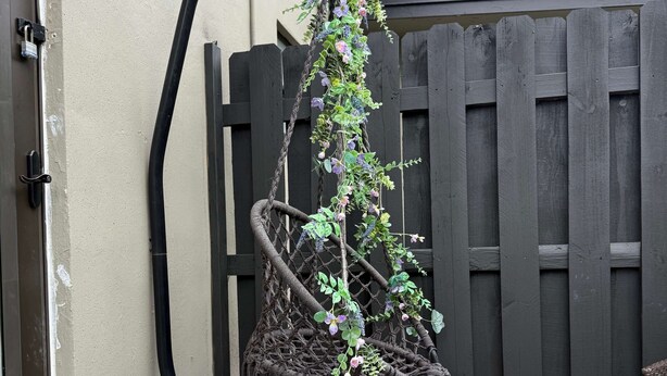 Un jardín con un enrejado, una cerca de madera y un piso con diseño.