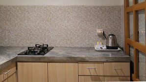 A kitchen with a gas stove, a kettle, and wooden cabinets. - d'Leisure (Kutuh)