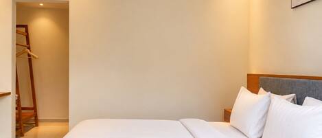 A hotel room with a bed, a nightstand, a wardrobe, and an air conditioning unit.