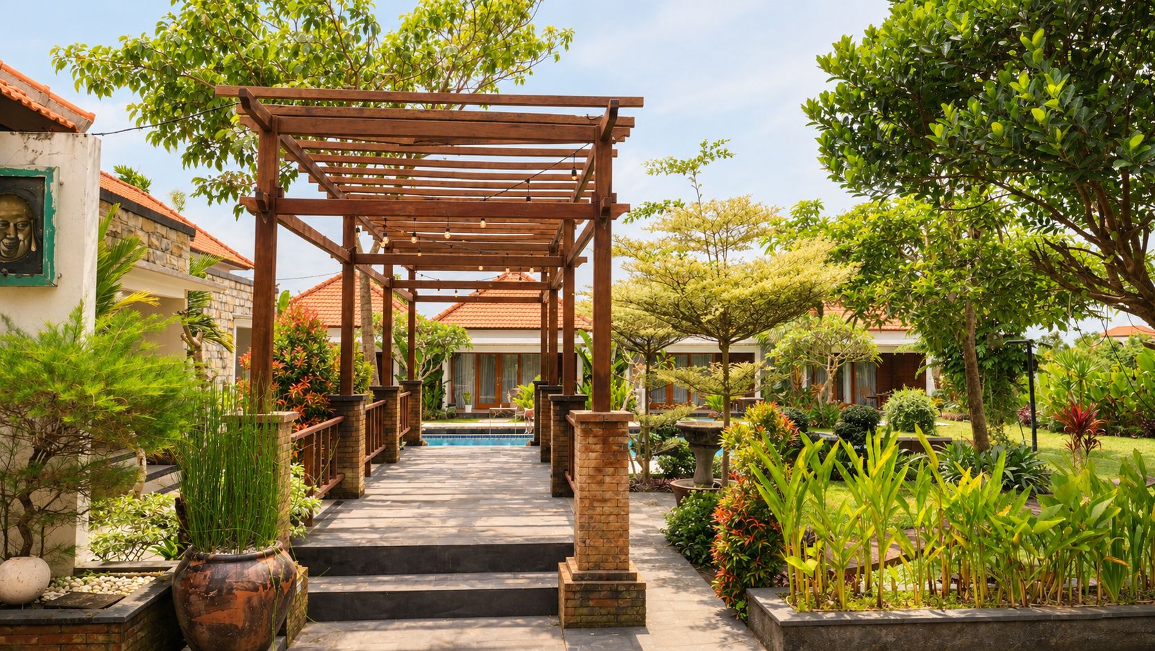 A covered walkway leading to a pool area, surrounded by lush greenery and potted plants.