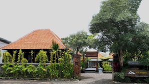 A building with a tiled roof, surrounded by lush greenery and a paved entrance. - d'Leisure (Kutuh)