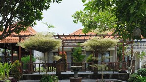 A garden with a pergola, a fountain, and a variety of plants. - d'Leisure (Kutuh)