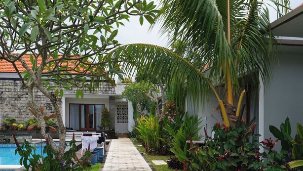 A pathway leading to a house with a pool, surrounded by lush greenery and tropical plants. - d'Leisure (Kutuh)