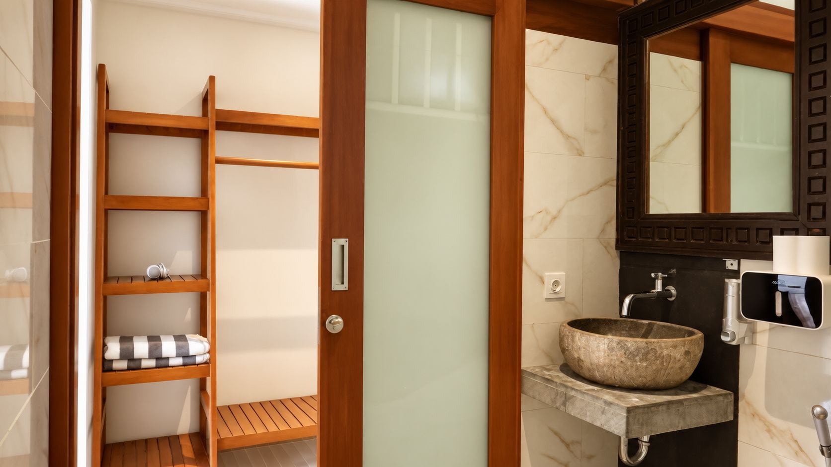 Een badkamer met een houten plankensysteem, een stenen wastafel en een grote spiegel.