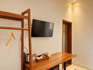 A room with a wooden desk, a flat-screen TV mounted on the wall, and a door leading to another room. - d'Leisure (Kutuh)