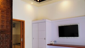 A bedroom with a bed, wardrobe, TV, and a small table with bottles. - d'Leisure (Kutuh)