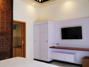 Un dormitorio con cama, armario, televisor y una pequeña mesa con botellas.