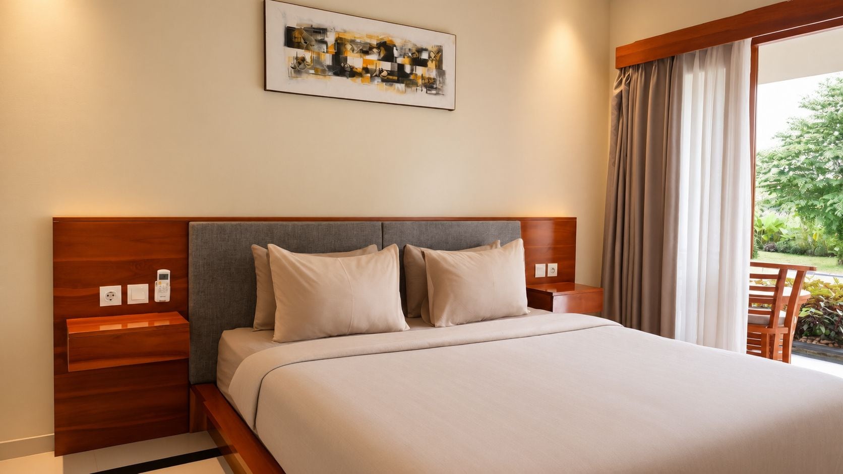 A hotel room with a bed, a headboard, a bedside table, a nightstand, a power outlet, a telephone, and a window with curtains.