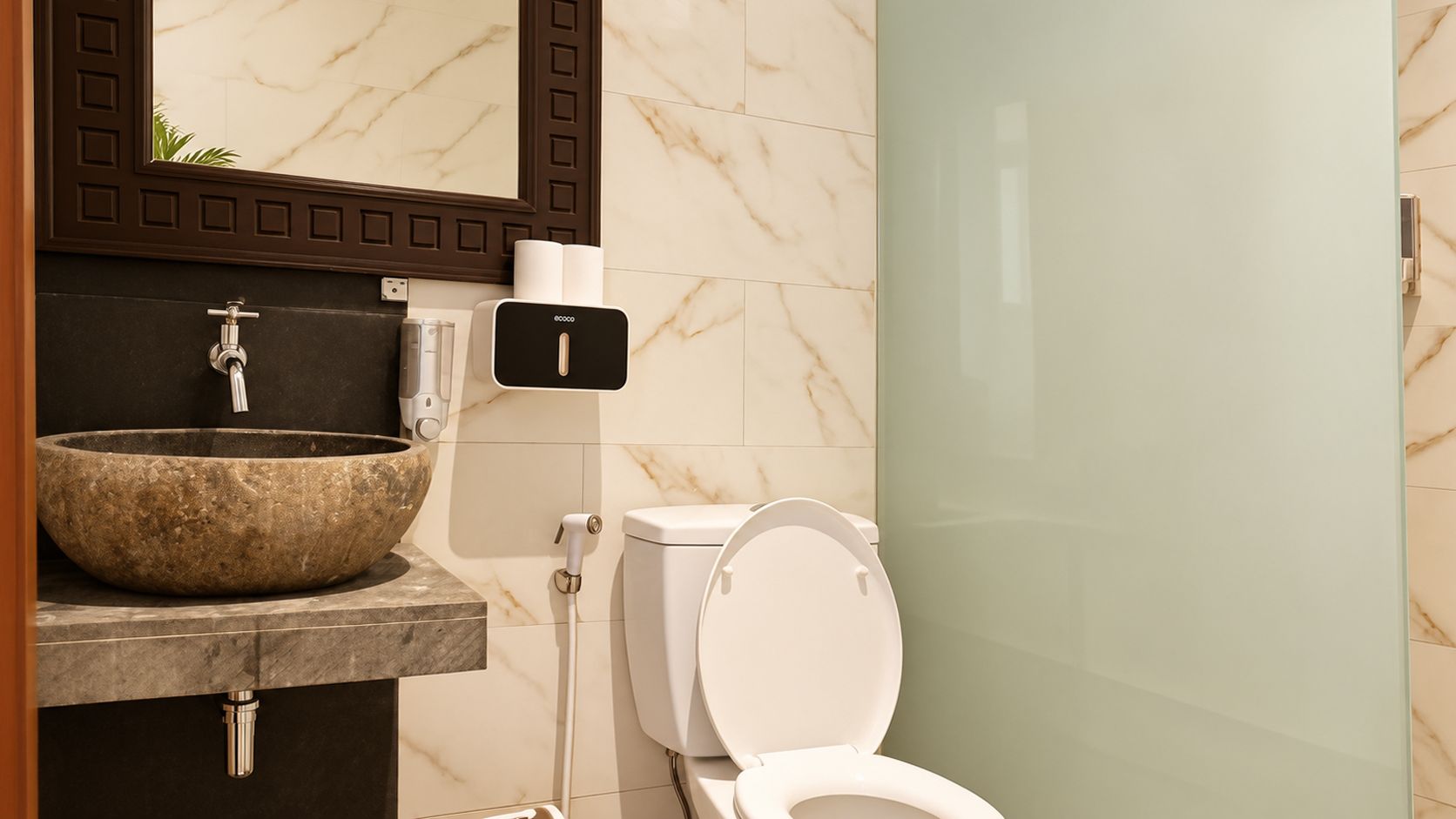 A bathroom with a stone sink, a toilet, and a glass shower enclosure.