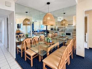 A modern dining area with a glass table, wooden chairs, and woven pendant lights. - Coastal Chic | YT S406 2BR (Myrtle Beach)