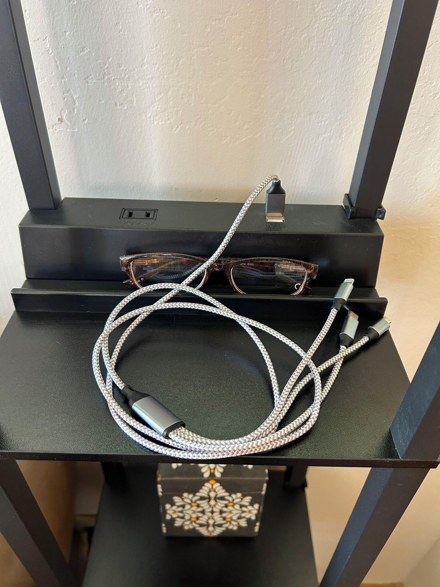Um dispositivo eletrônico preto com um cabo e um par de óculos em cima.