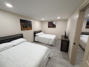 A bedroom with two beds, a TV, and artwork on the walls.