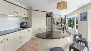 Una cocina moderna con una isla curva, armarios blancos y una lámpara colgante.