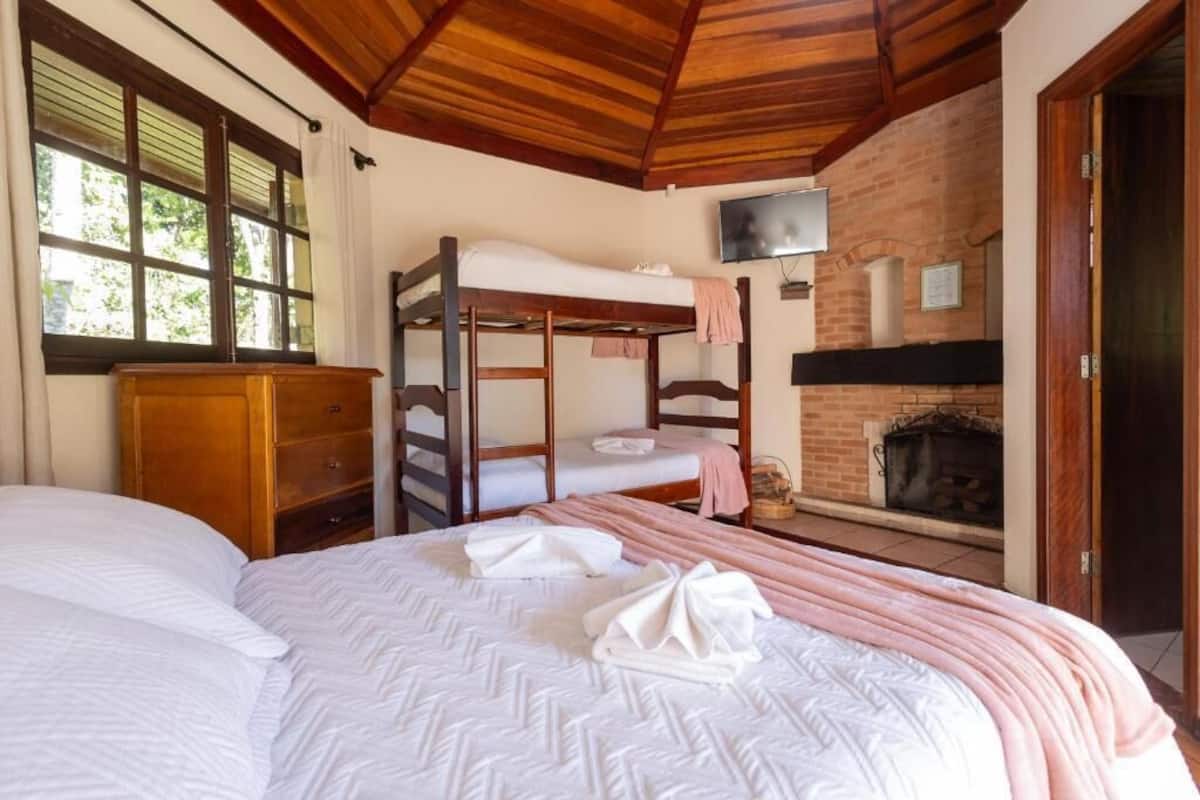 Una habitación con literas, chimenea, televisor y techo de madera.