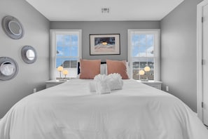 Una habitación de hotel con una cama grande, dos mesitas de noche, un cuadro en la pared y una ventana con persianas.
