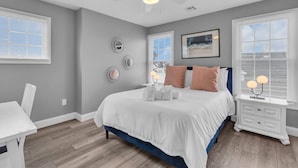 Un dormitorio con cama, mesita de noche, escritorio y ventilador de techo.