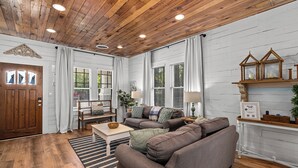 A cozy living room with a wooden ceiling, white walls, and a large sofa.
