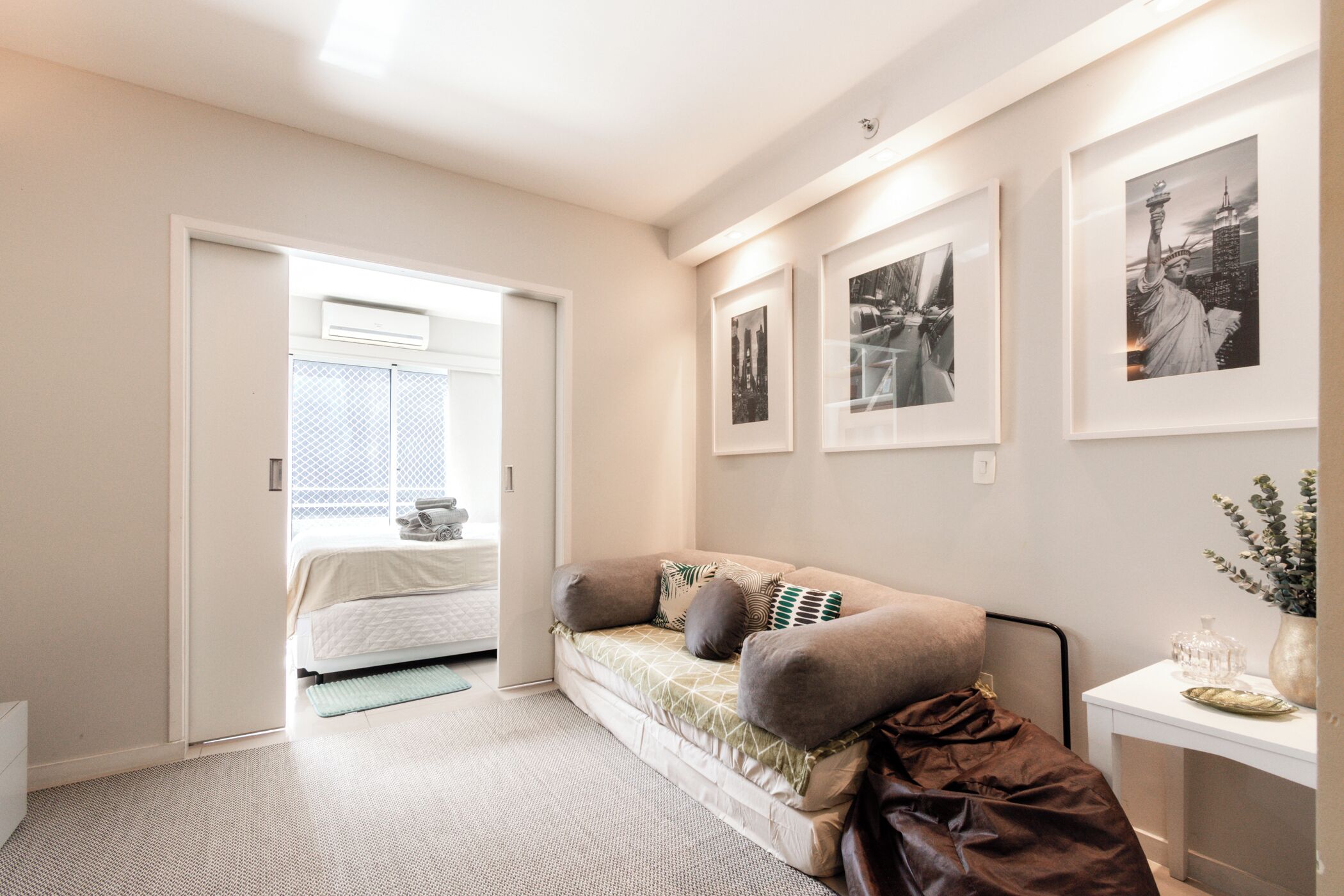 A bedroom with a bed, a sofa, a bedside table, and framed pictures on the wall.