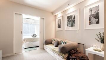 A bedroom with a bed, a sofa, a bedside table, and framed pictures on the wall.