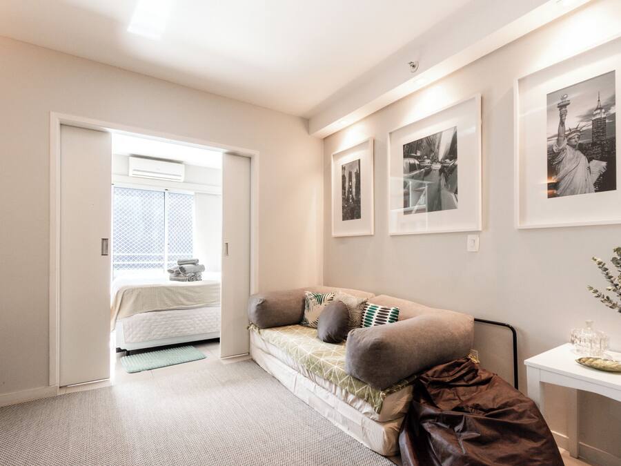 A bedroom with a bed, a sofa, a bedside table, and framed pictures on the wall.