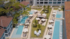 Een resort met meerdere zwembaden, comfortabele zitgedeeltes en uitzicht op de oceaan.
