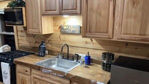 Une cuisine avec des meubles en bois, un évier en acier inoxydable, un four à micro-ondes et une cuisinière.