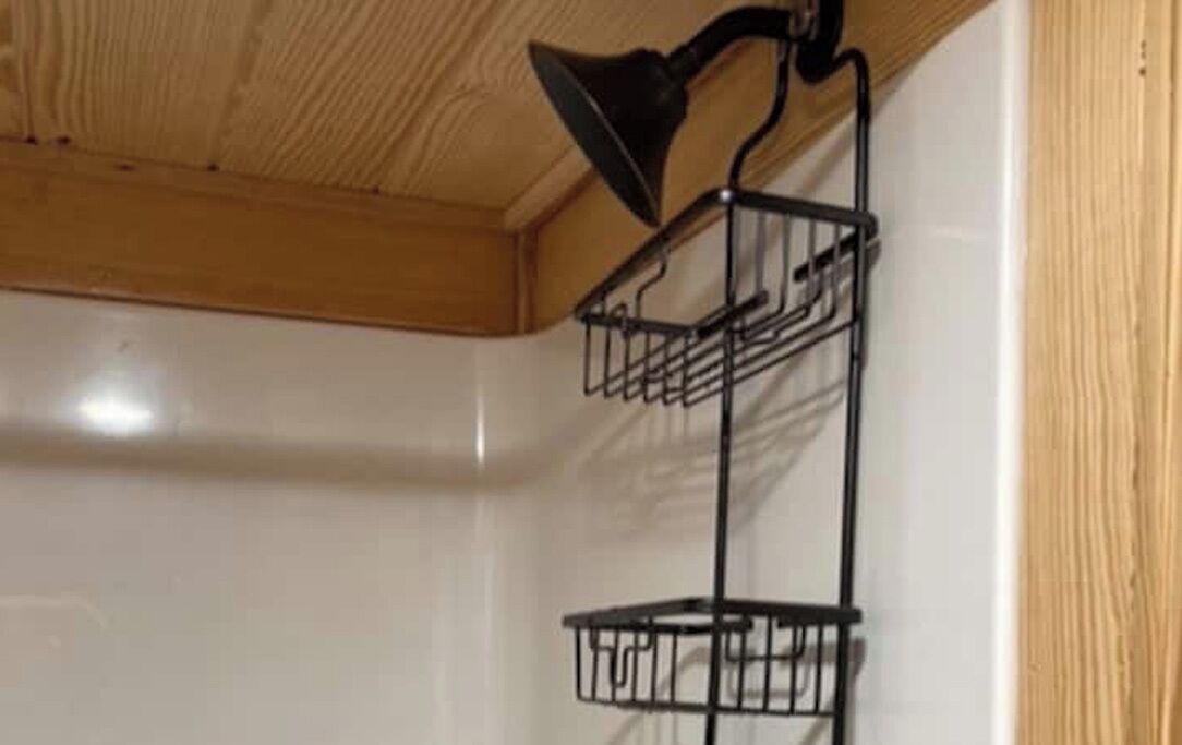 A corner with a black metal shelf unit against a white wall, a wooden ceiling, and a wooden trim.