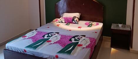 A bedroom with a bed, a nightstand, a wall-mounted light, and a small window.